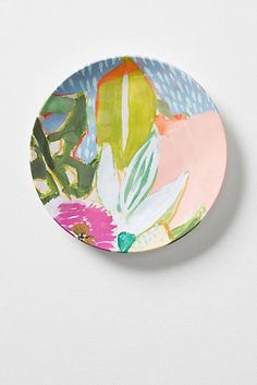 a plate with flowers painted on it sitting on a white surface next to a wall