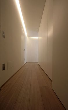 an empty hallway with white walls and wooden floors