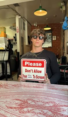 a man holding up a sign that says please don't allow your to scream