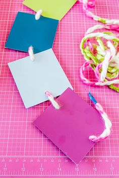 three pieces of paper are being sewn together on a piece of pink and green fabric