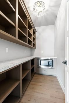 an empty room with wooden shelves and white walls, including a microwave oven in the corner