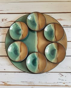 four green and brown bowls on a plate with white wood planks in the background