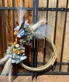 a wreath with feathers and flowers is placed in front of a fence