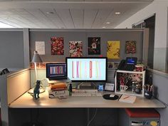 an office cubicle with two computer monitors on the desk and several other items in front of it