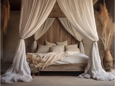 a bed with white drapes and pillows on it