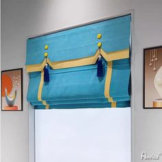 a blue and yellow roman blind with tassels hanging from it's sides