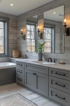 a bathroom with two sinks, mirrors and a bathtub in front of three windows