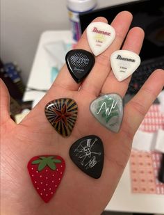 a hand holding six different colored rocks in it's palm with writing on them