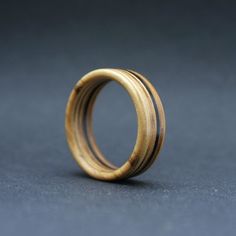 a wooden ring sitting on top of a gray table next to a black surface with an object in the middle