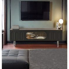 a flat screen tv mounted to the side of a wall next to a gray couch