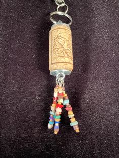 a cork keychain with beads hanging from it's side on a black surface