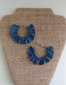 a pair of blue fabric hoop earrings sitting on top of a piece of burlock