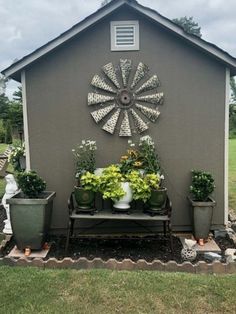 a garden shed with potted plants on the side and a windmill decoration above it