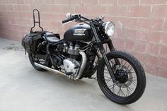 a black motorcycle parked next to a brick wall