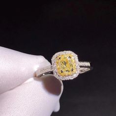 a yellow and white diamond ring in someone's hand