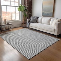 a living room with a white couch and wooden flooring next to a large window