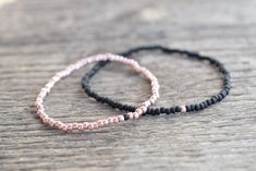 two beaded bracelets sitting on top of a wooden table next to each other