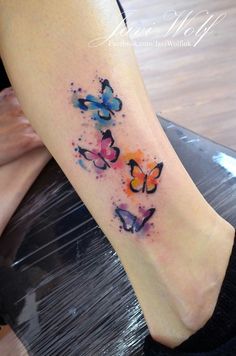 a woman's foot with watercolor butterflies tattoo on the left side of her leg