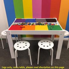 a table and chairs with legos on it in front of a rainbow colored wall