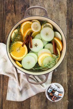 a pot filled with sliced oranges, apples and cinnamon on top of a wooden table