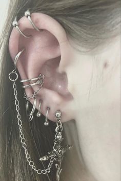 a close up of a person with ear piercings and chains on their backseats