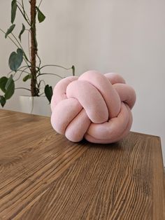 a pink knot sitting on top of a wooden table next to a potted plant