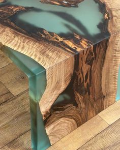 a table made out of wood with blue glass in the top and bottom section, on wooden flooring