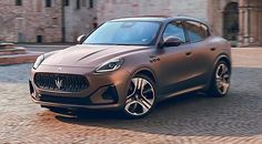 a grey masera is parked in front of a brick building on a cobblestone street