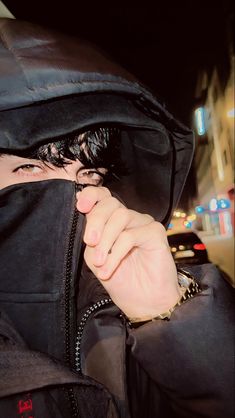 a person wearing a hooded jacket and holding their face to the side with both hands