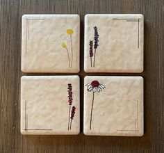 four coasters with flowers painted on them