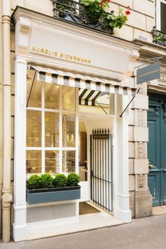 an outside view of a store front with flowers in the window and plants on the windowsill