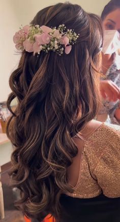 the back of a woman's head with long hair and flowers in her hair