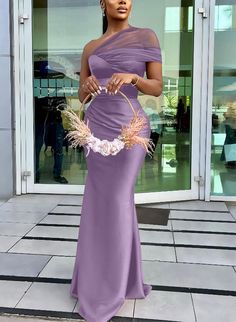 a woman in a long purple dress holding a basket with flowers on it and posing for the camera