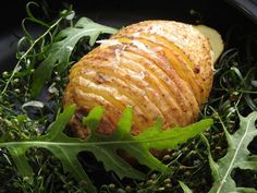 an apple is sitting in the middle of some green leaves and grass on top of a black plate