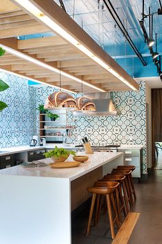 a kitchen with wooden stools next to a counter and an island in the middle