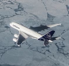 an airplane is flying over the ice in the ocean or sea water with it's landing gear down