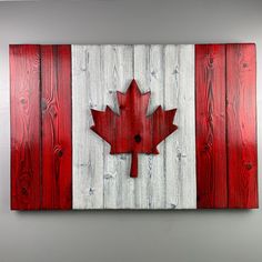 a wooden canadian flag with a red maple leaf on it's side, hanging on a wall