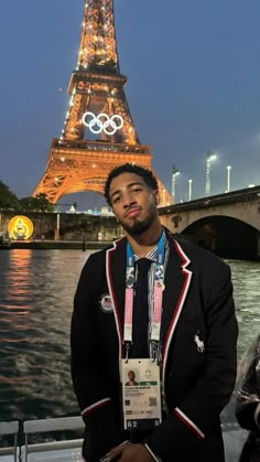 a man standing in front of the eiffel tower with his medal around his neck