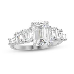 an emerald cut diamond ring with baguetts on the shoulders and side stones set in 18k white gold