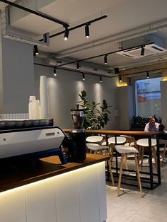 a coffee machine sitting on top of a counter next to a white table and chairs