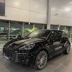 a black porsche cayen is parked in a showroom