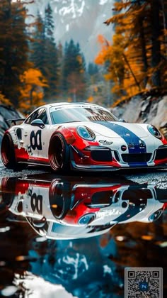 a red, white and blue sports car parked in front of a lake with trees