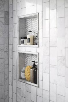 two bathroom shelves with soap, shampoo and other items on them in a white tiled wall