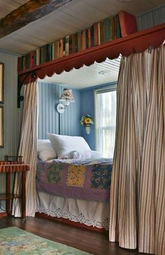 a bed sitting under a window next to a book shelf in a room filled with books