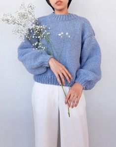 a woman wearing a blue sweater holding flowers