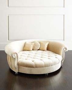 a round couch sitting on top of a hard wood floor next to a white wall