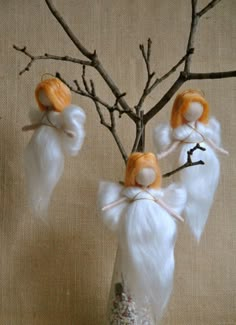 three little white angel figurines hanging from a tree branch