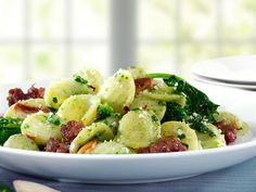 a white bowl filled with pasta and broccoli on top of a blue table cloth