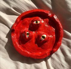 a red object with eyes on it laying on a bed