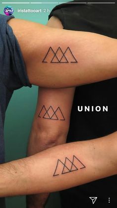 two men with matching tattoos on their arms, one is holding the other's arm